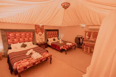 a bedroom with two beds and a tent at Imperial Glory Lodges in Merzouga