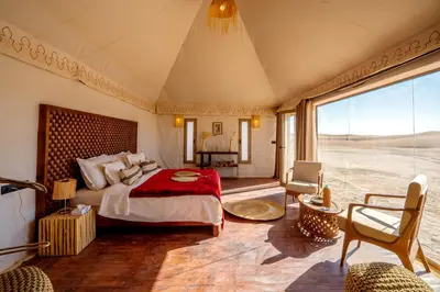 a bedroom with a bed and a large window at Ghazala Camp - Luxury Erg Chigaga Magic in Mhamid