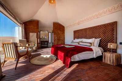 a bedroom with a large bed with a red blanket at Ghazala Camp - Luxury Erg Chigaga Magic in Mhamid