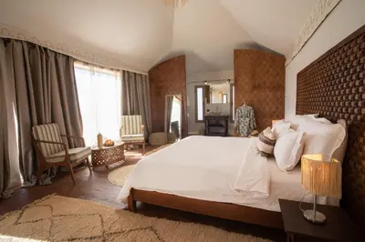 a bedroom with a large bed and a mirror at Ghazala Camp - Luxury Erg Chigaga Magic in Mhamid
