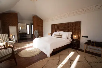 a bedroom with a large white bed and a mirror at Ghazala Camp - Luxury Erg Chigaga Magic in Mhamid
