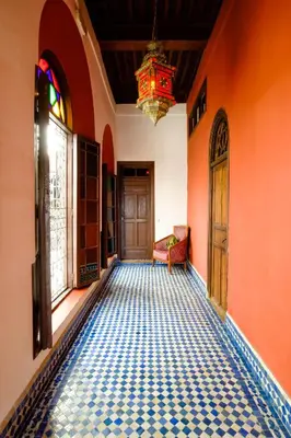 a hallway with orange walls and a floor with a chandelier at Riad Tafilalet in Fès