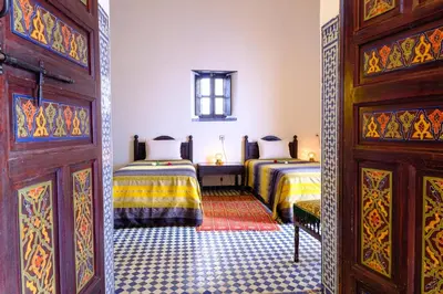 a bedroom with two beds and a door at Riad Tafilalet in Fès