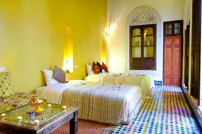 a hotel room with two beds and a table at Riad Tafilalet in Fès