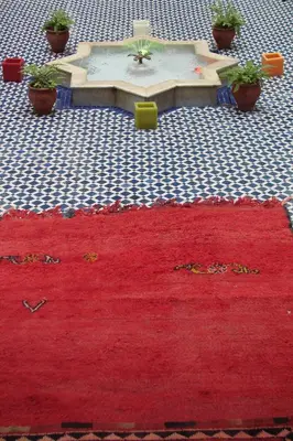 a red rug on the floor in front of a table at Riad Tafilalet in Fès