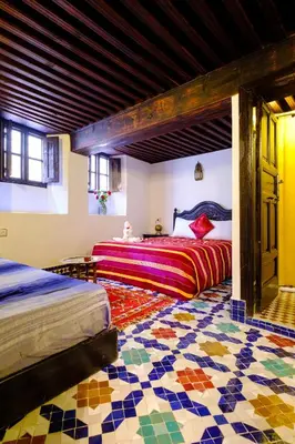 a bedroom with two beds and a mosaic floor at Riad Tafilalet in Fès