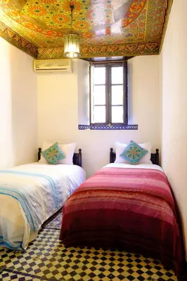 two beds in a room with a ceiling at Riad Tafilalet in Fès