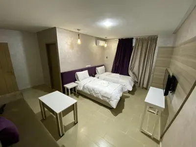 a bedroom with a bed and two tables in it at HOTEL CHARk in Guercif