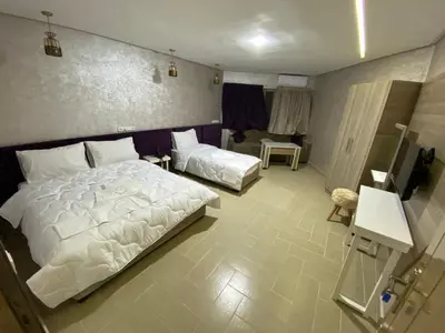 a bedroom with two beds and a television in it at HOTEL CHARk in Guercif
