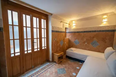 a bedroom with two beds and a wooden door at Dar Kenz Fes in Fès