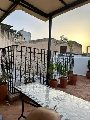 a patio with a table and potted plants on a balcony at Dar Kenz Fes in Fès