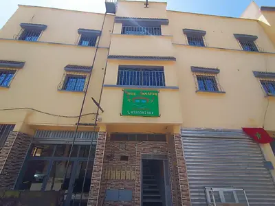 a building with a green sign on the side of it at Hotel ASSAFIRE in Bou Mia