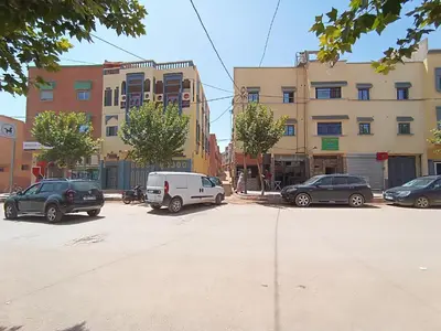 a parking lot with cars parked in front of buildings at Hotel ASSAFIRE in Bou Mia