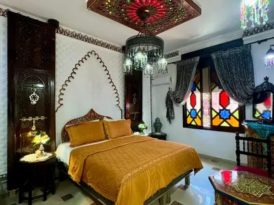 a bedroom with a bed and stained glass windows at Riad Mogador in Meknès