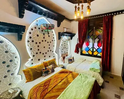 a bedroom with two beds and a wall with windows at Riad Mogador in Meknès