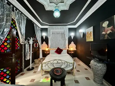 a bedroom with a bed and a tv in it at Riad Mogador in Meknès