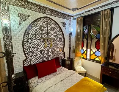 a bedroom with a bed and a stained glass window at Riad Mogador in Meknès