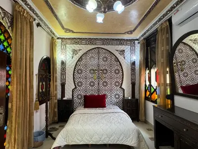 a bedroom with a bed with a red pillow at Riad Mogador in Meknès