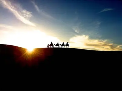 a group of people riding horses on a hill at sunset at Sahara Events Camp in Merzouga