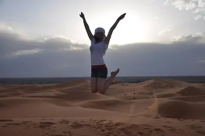 a woman jumping in the sand in the desert at Sahara Events Camp in Merzouga
