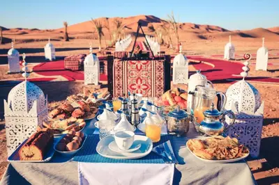 a table with plates of food on it in the desert at Sahara Events Camp in Merzouga
