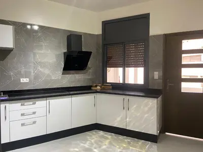 a kitchen with white cabinets and black counter tops at Bloemen Huis in Fès