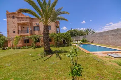 a house with a palm tree and a swimming pool at Kasbah Roseville in Ait Sedrate Sahl Gharbia