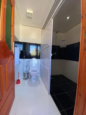 a bathroom with a toilet with a glass shower stall at Kasbah Roseville in Ait Sedrate Sahl Gharbia