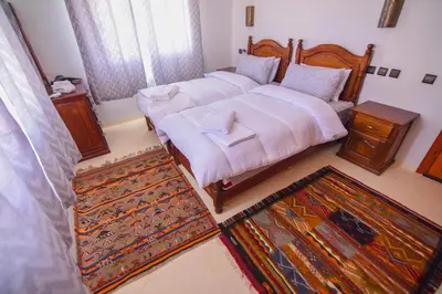 a bedroom with two twin beds and a rug at Kasbah Roseville in Ait Sedrate Sahl Gharbia