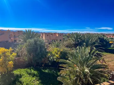 a view of a garden with palm trees and buildings at Kasbah Roseville in Ait Sedrate Sahl Gharbia
