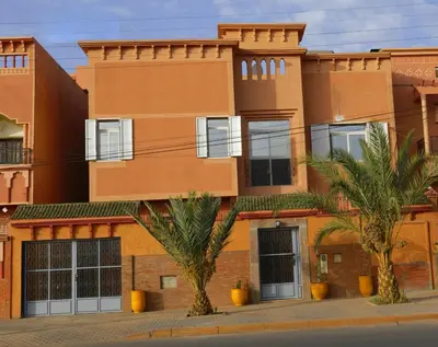 a building with palm trees in front of it at Riad Parfums de OUARZAZATE in Ouarzazate