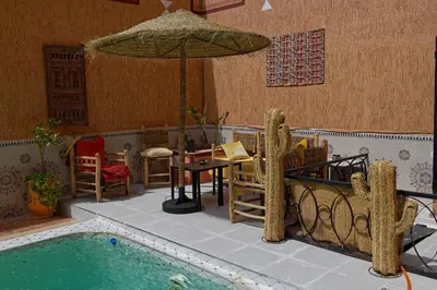 a patio with a table and an umbrella next to a pool at Riad Parfums de OUARZAZATE in Ouarzazate