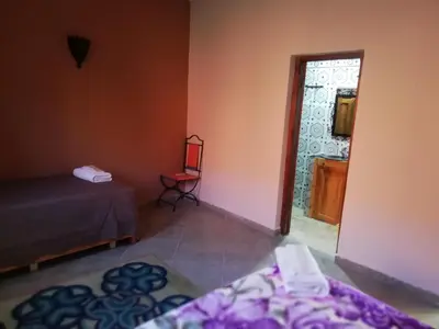 a room with a bed and a chair and a window at Riad Ouinz in Aït Ben Haddou
