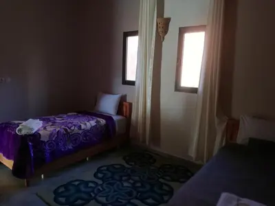 a small room with two beds and two windows at Riad Ouinz in Aït Ben Haddou