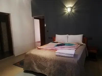 a bedroom with a bed with a light on the wall at Riad Ouinz in Aït Ben Haddou