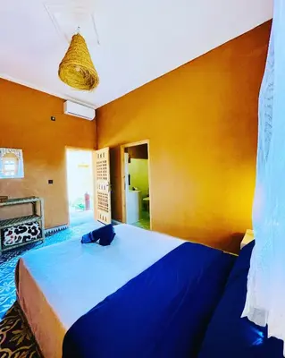 a bedroom with a blue bed and a yellow wall at Tigmi Timhar in Tafrourht nʼAït Bou Jijou