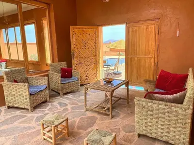 a living room with chairs and a table and a window at Tigmi Timhar in Tafrourht nʼAït Bou Jijou