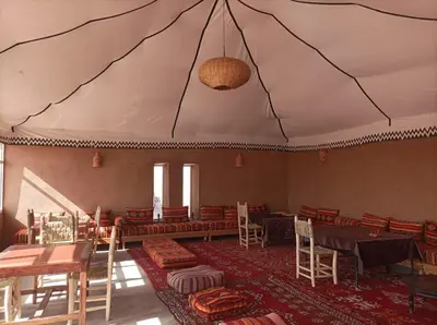 a dining room with tables and chairs and a ceiling at Excreción erg chegaga 2 jour départ zagora 4x4 in Zagora