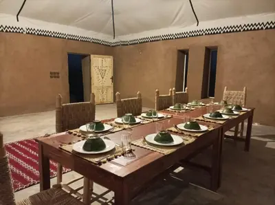 a room with a long wooden table and chairs at Excreción erg chegaga 2 jour départ zagora 4x4 in Zagora