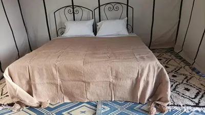 a bed with a metal headboard and white pillows at Excreción erg chegaga 2 jour départ zagora 4x4 in Zagora
