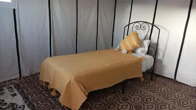 a bedroom with a bed with a blanket and pillows at Excreción erg chegaga 2 jour départ zagora 4x4 in Zagora