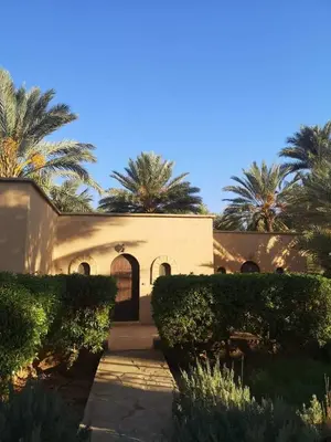 a building with palm trees in front of it at AUBERGE DES ANGES in Zrigat