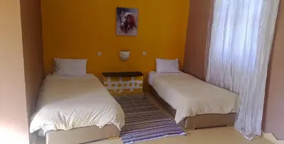 two beds in a room with yellow walls at AUBERGE DES ANGES in Zrigat