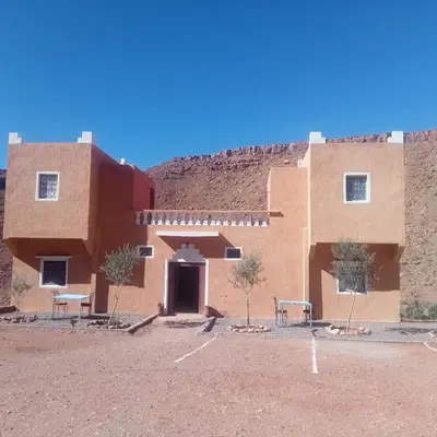 a building in the desert with two benches in front at Dar Brahim Resto Beds in Ouarzazate