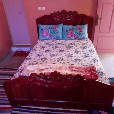 a bedroom with a large bed with a wooden headboard at Dar Brahim Resto Beds in Ouarzazate