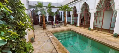 an indoor swimming pool in a building with trees at Riad Ramzi in Marrakech