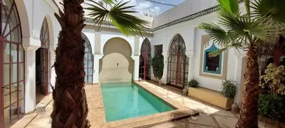 an indoor swimming pool in a house with a palm tree at Riad Ramzi in Marrakech