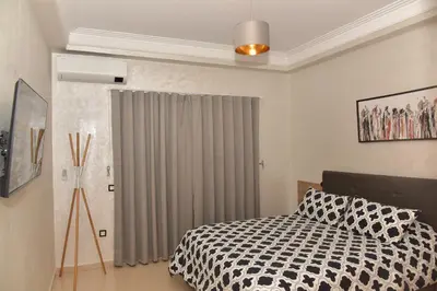a bedroom with a bed and a window with curtains at Golf Royal appartement in Fès