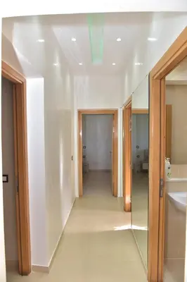 a hallway of a bathroom with a sink and a mirror at Golf Royal appartement in Fès