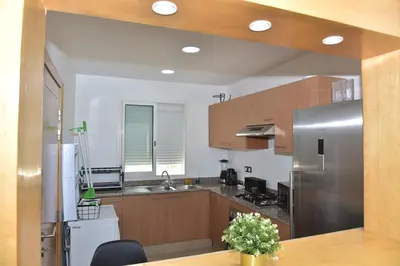 a kitchen with wooden cabinets and a stainless steel refrigerator at Golf Royal appartement in Fès